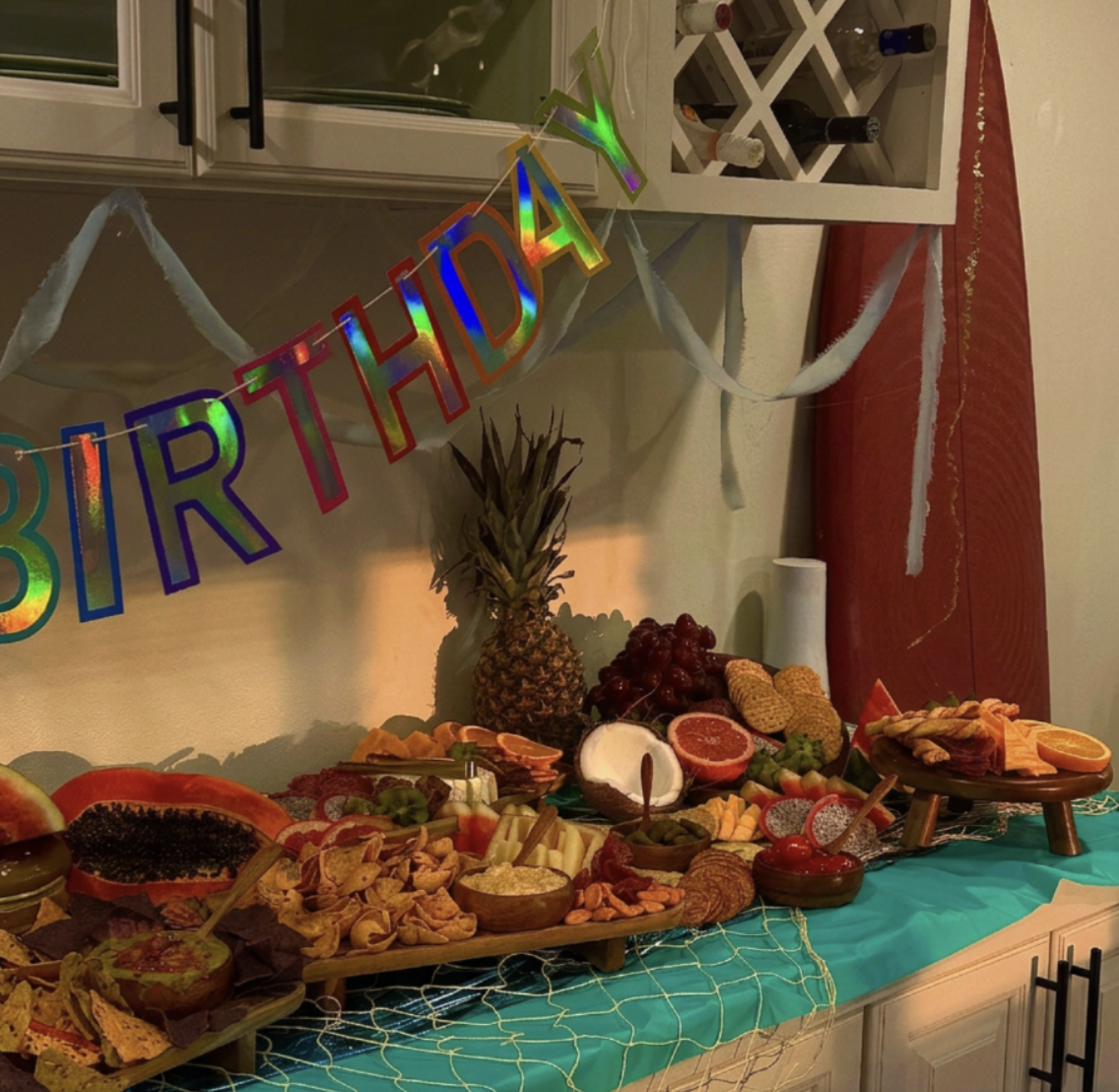 Long tropical birthday grazing table set along a teal cloth
