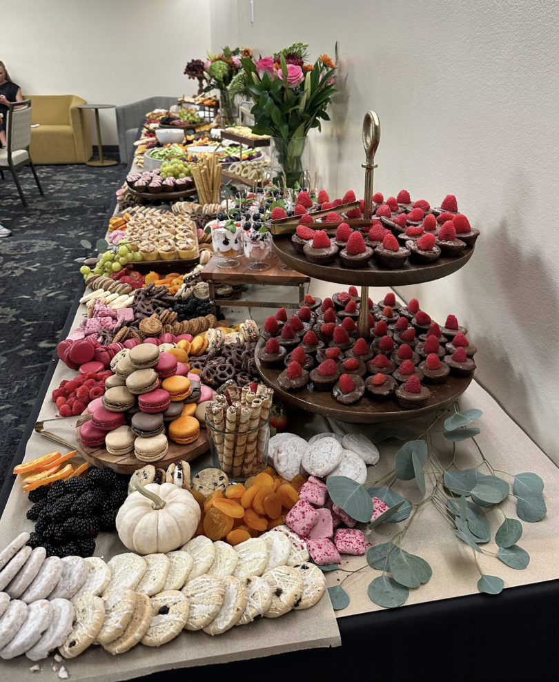 Long dessert table with macarons, chocolate raspberry tarts, cookies and florals