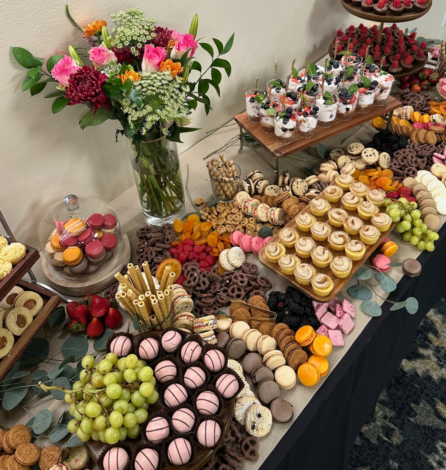Dessert table with cupcakes, macarons, berries and a bright bouquet